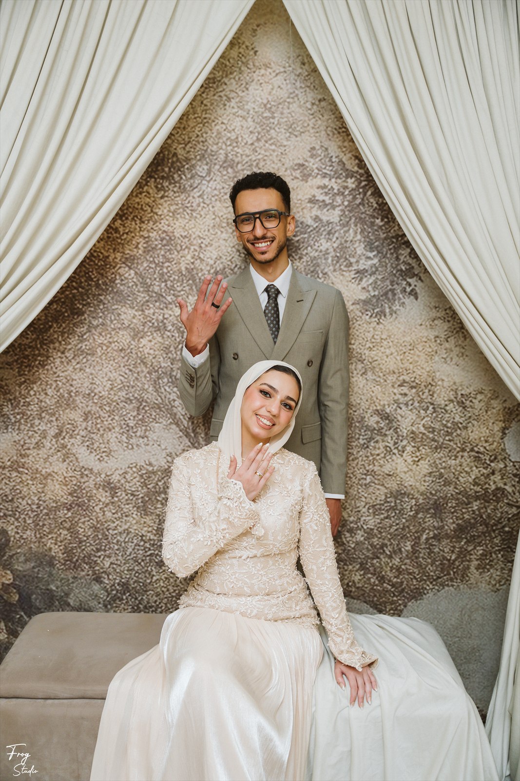 Mohamed standing behind Reem and waving at the camera while she sits smiling
