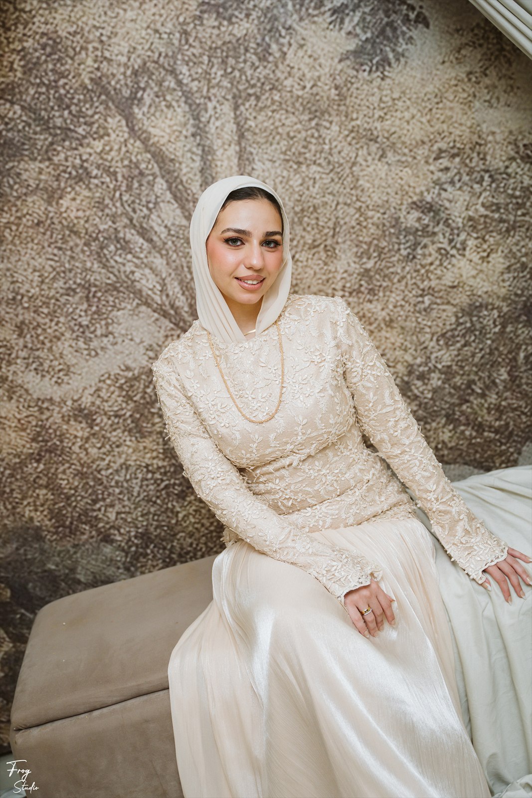 Reem seated in her hand-beaded ivory lace gown and veil, a fine gold chain around her neck