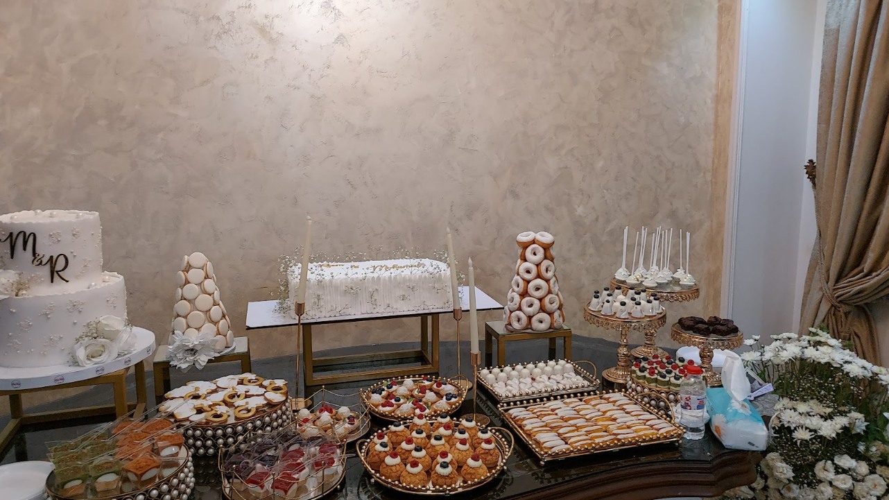 Wide view of the engagement sweet table with the monogram cake, macaron tower and gold platters