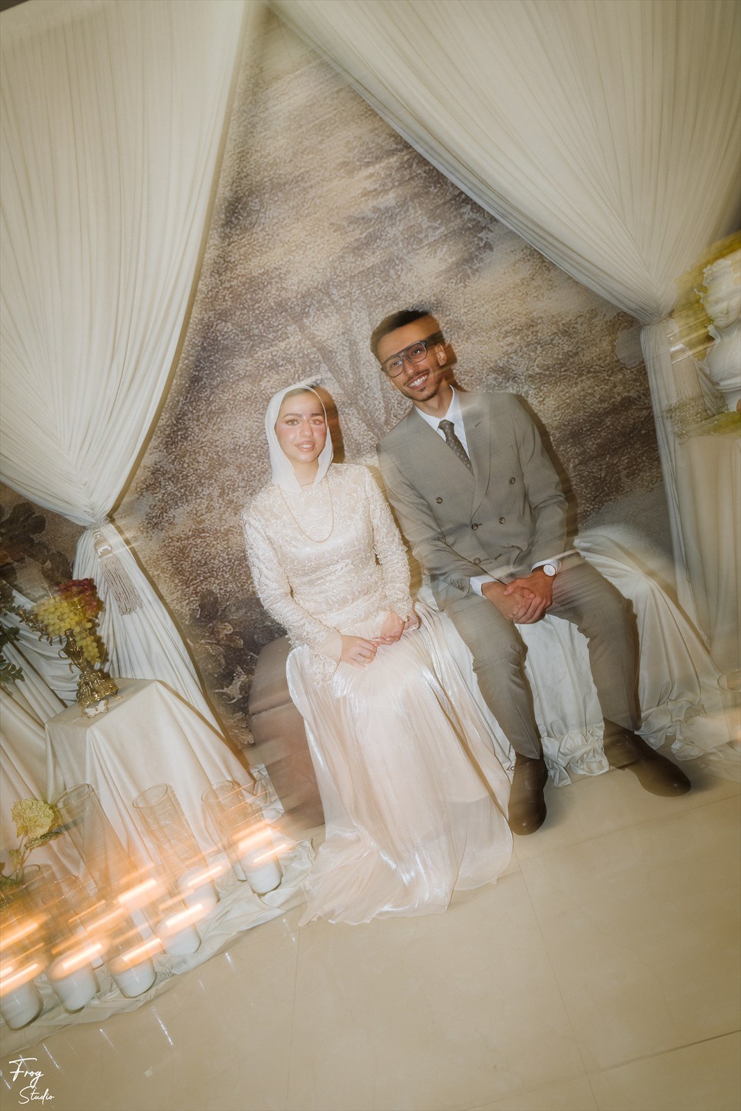 Reem and Mohamed seated together on the sofa, both looking at the camera