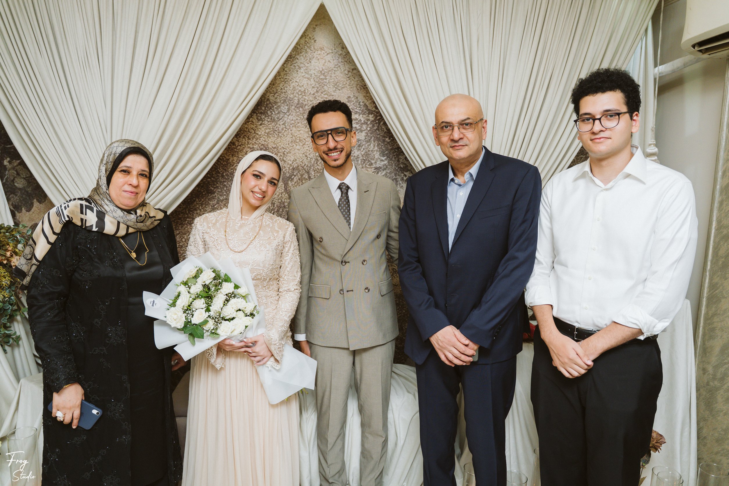 Mohamed and Reem with three family members in front of the engagement backdrop