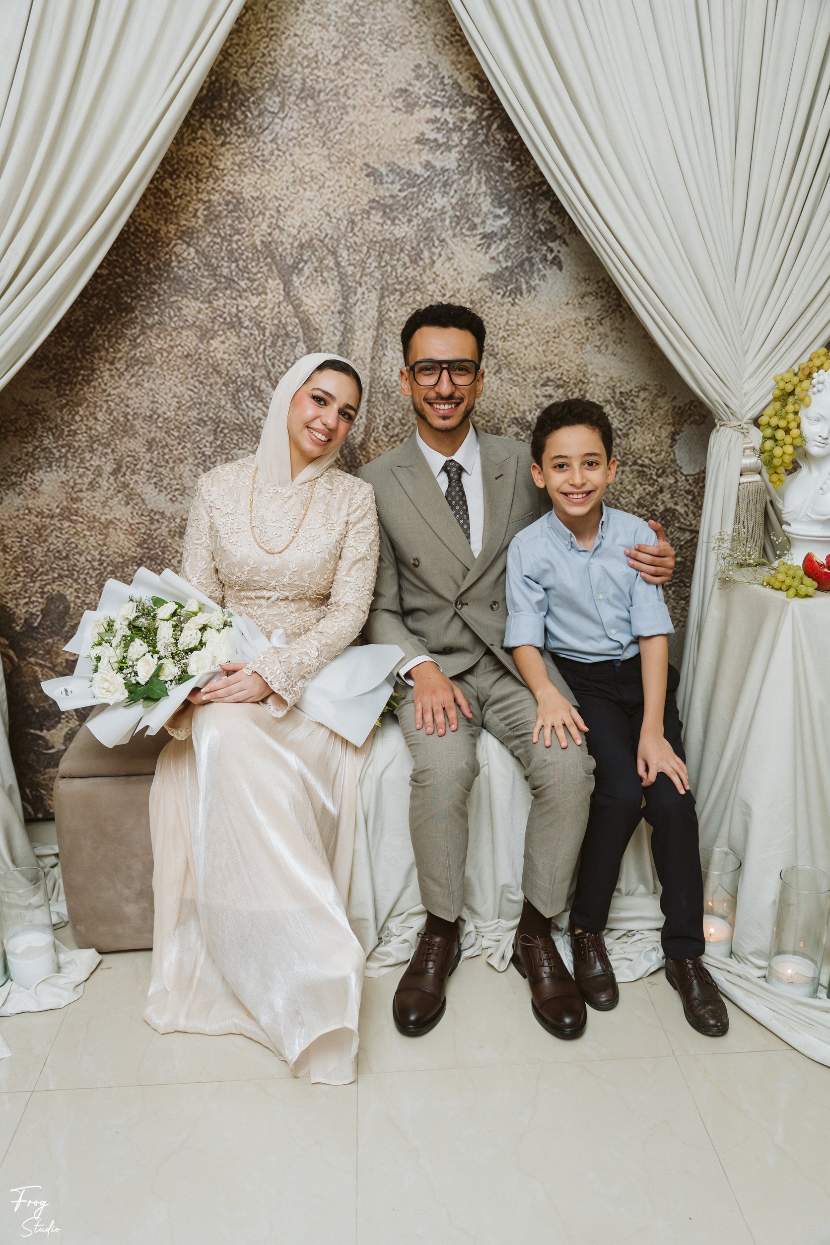 Mohamed and Reem seated together with a young boy beside them, all smiling