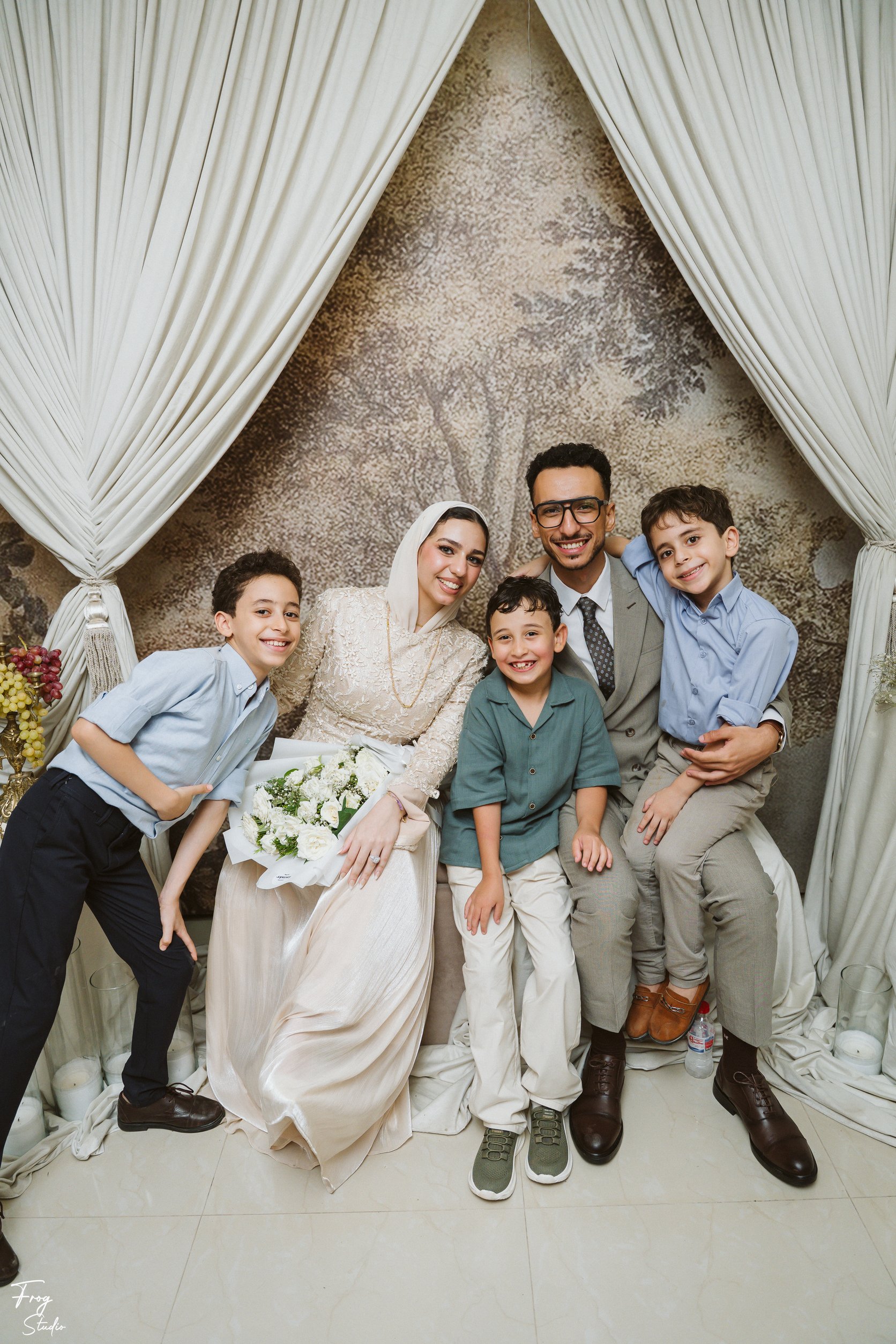 Mohamed and Reem surrounded by three smiling boys at the engagement backdrop