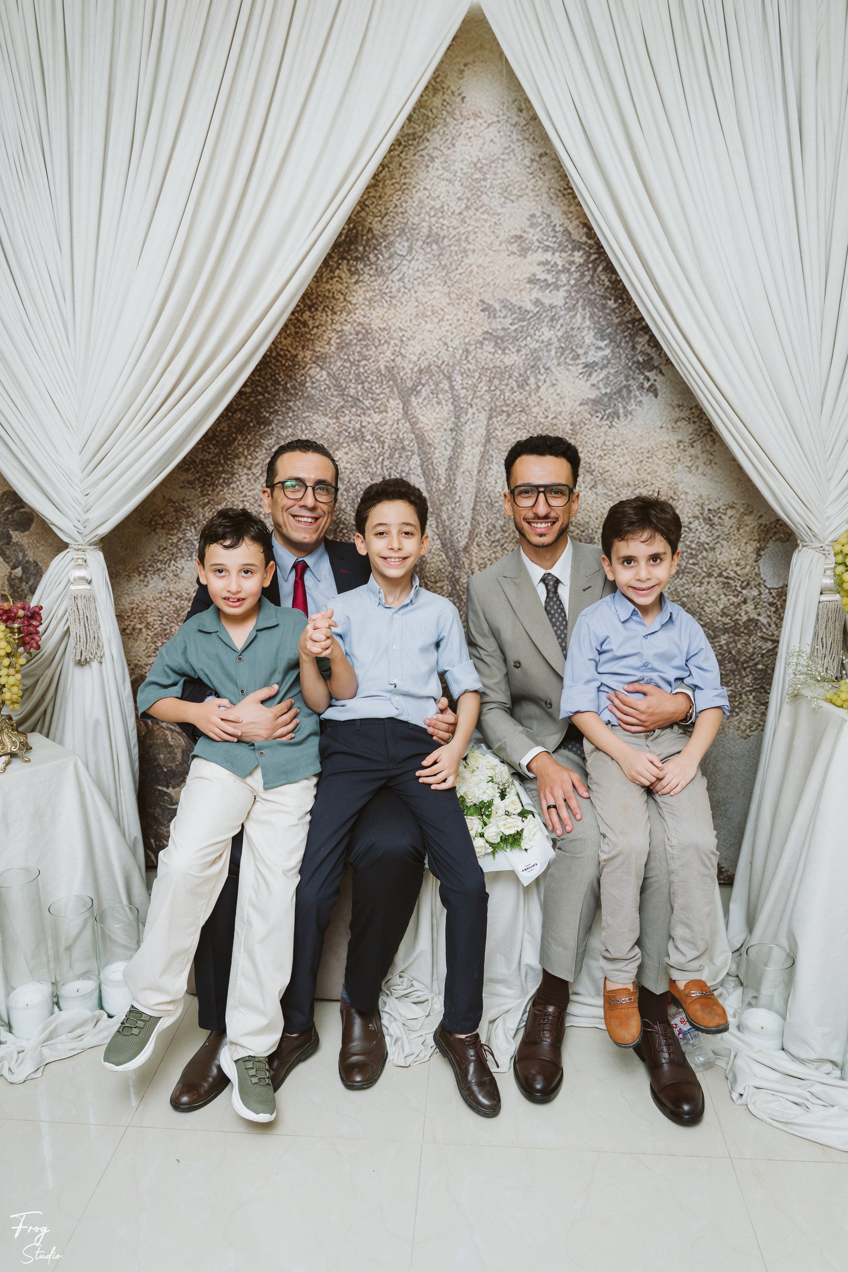 Mohamed and another gentleman seated with four young boys, arms around each other