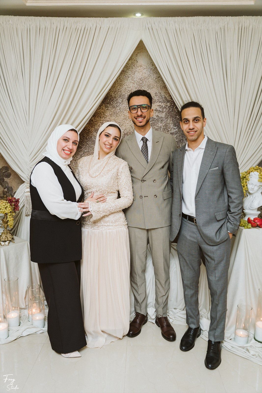 Reem and Mohamed with two family members in front of the draped backdrop