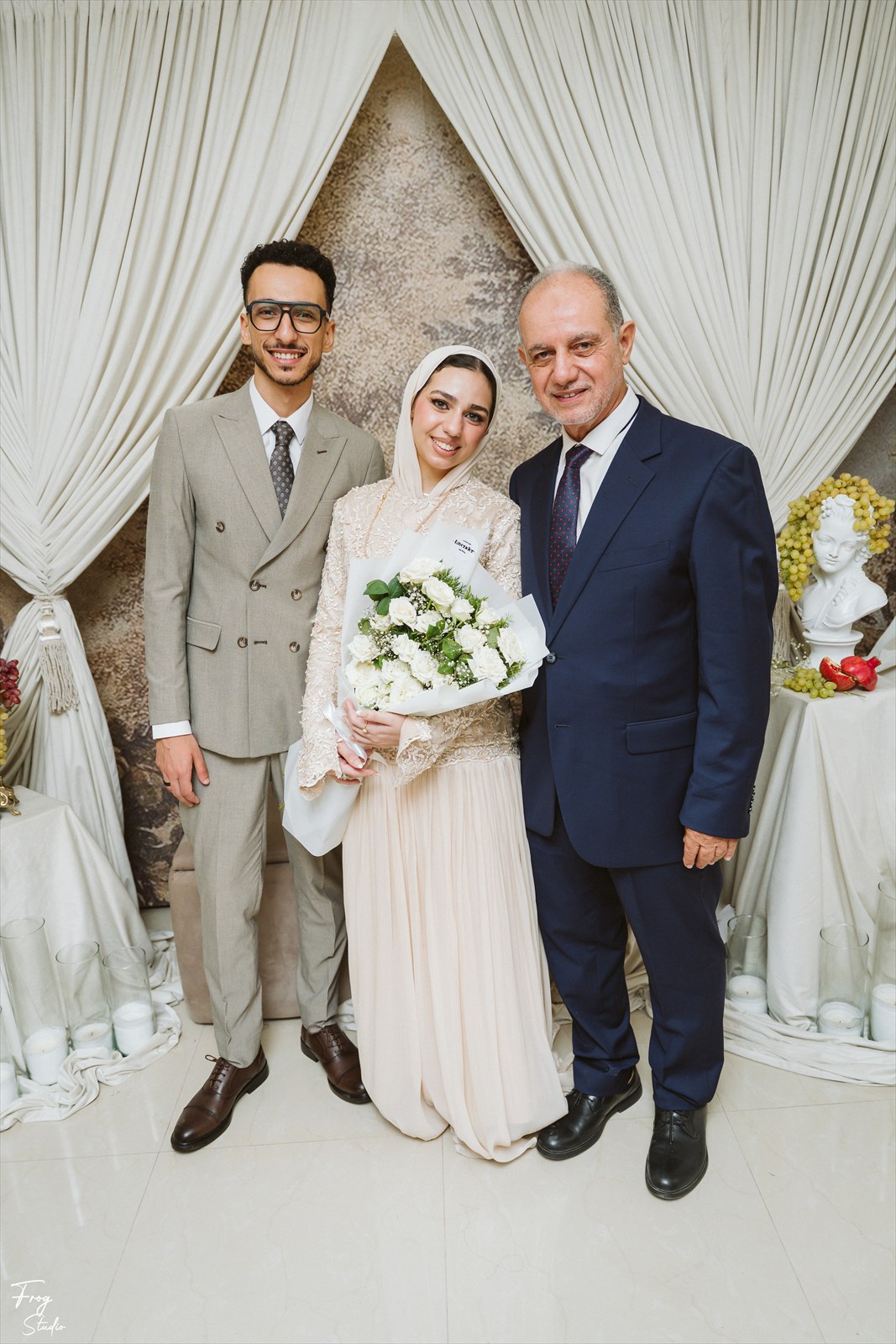 Reem and Mohamed standing with two family members in front of the drapes