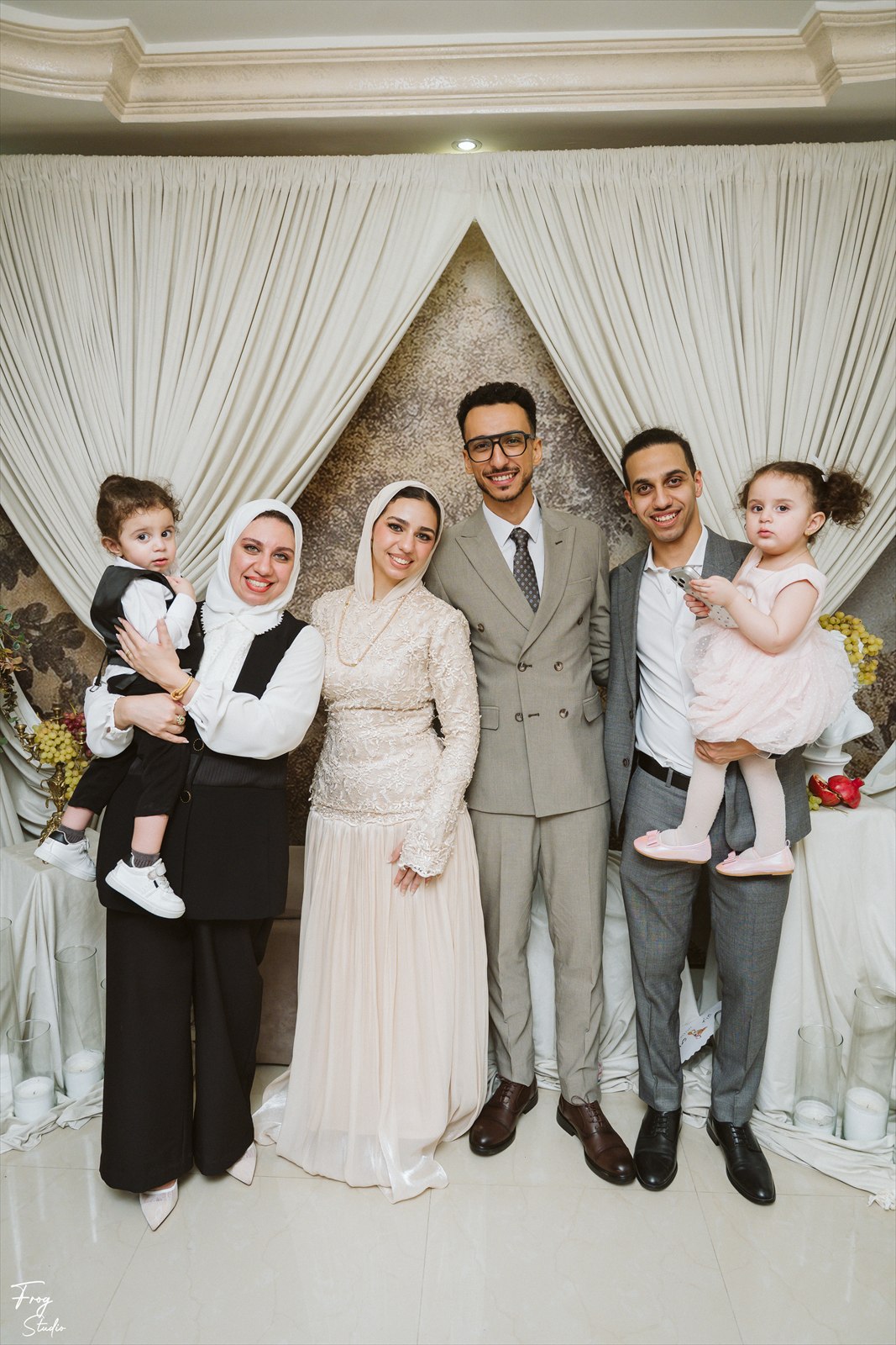 Reem and Mohamed with family members in front of the draped backdrop